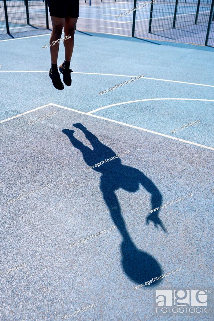 Stock Photo: Shadow of a man playing basketball on basketball court, dunking.
