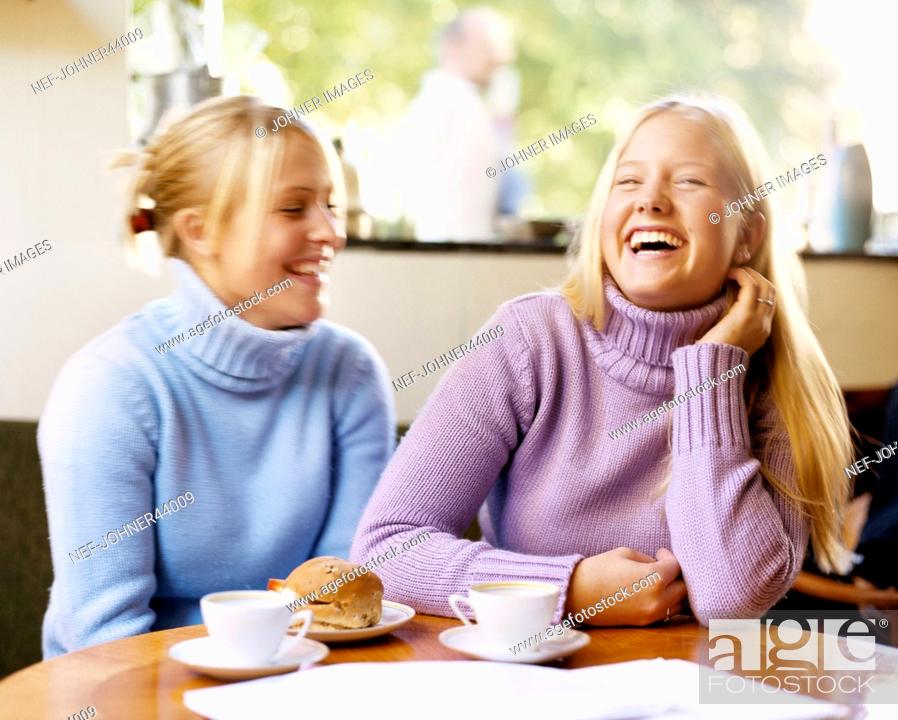 Stock Photo: Laughing women sitting at the table and have coffee.