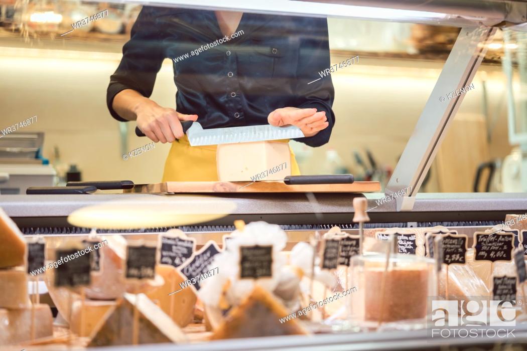 Stock Photo: Shop clerk woman sorting cheese in the supermarket display to sell it.