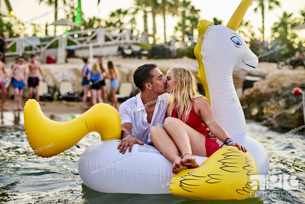 Stock Photo: Greece, Crete, Chersonissos, couple at Beach Party sitting on inflatable, kissing, romantic.