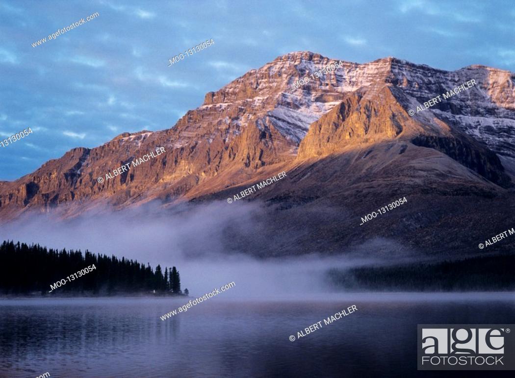Stock Photo: Rocky mountain fog over lake sunset.