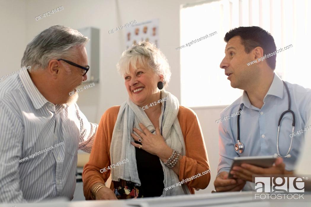 Stock Photo: Doctor meeting with happy senior couple in doctors office.