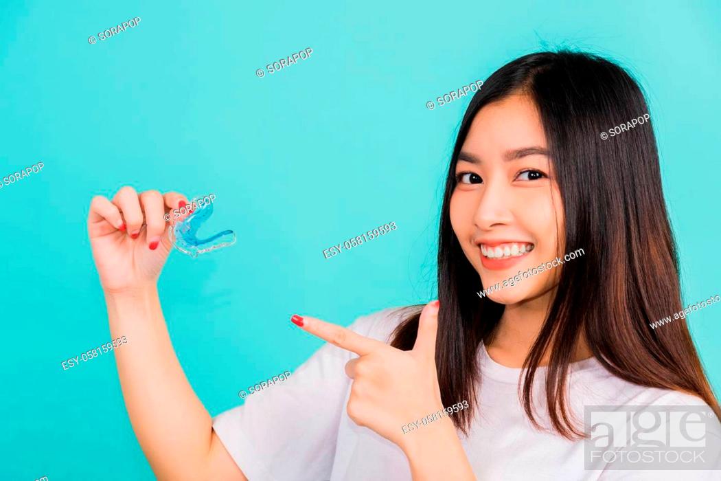 Stock Photo: Portrait young Asian beautiful woman smiling pointing with finger silicone orthodontic retainers for teeth, Female hold teeth retaining tools after removable.