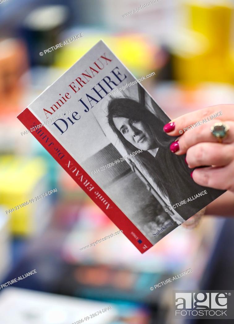 Stock Photo: 06 October 2022, Saxony, Leipzig: A woman holds the book ""The Years"" by Annie Ernaux in her hands in a Leipzig bookstore, published by Suhrkamp verlag.