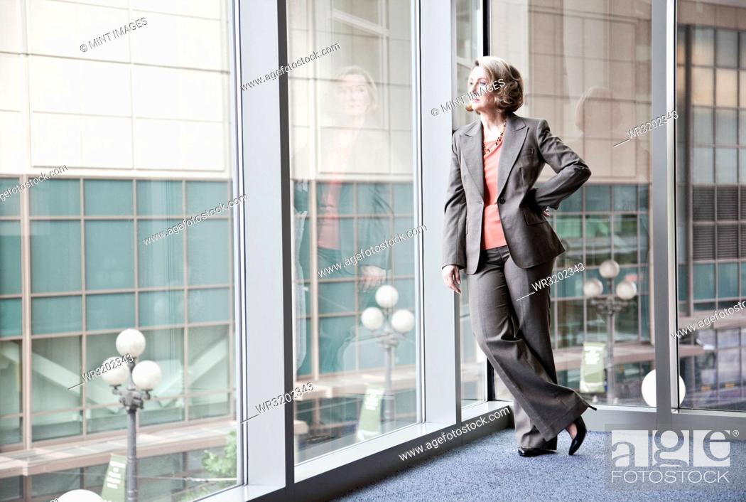 Stock Photo: A Caucasian businesswoman standing next to a large window in a convention centre lobby.