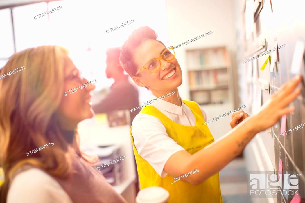 Photo de stock: Smiling, confident creative businesswomen planning, brainstorming at blackboard.