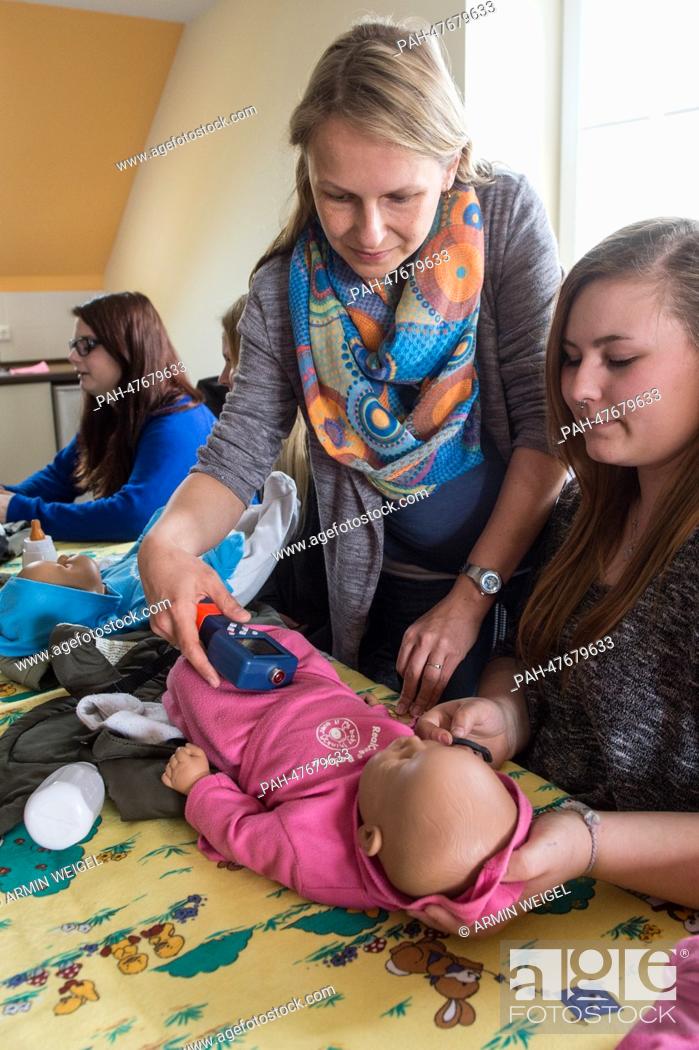 Stock Photo: Social worker Julia Wiesend (C )shows some teenage girls how to swaddle a baby during an internship for parents to prevent young people to get children in.