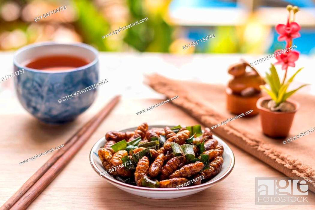 Stock Photo: Fried insects - Wood worm insect crispy with pandan after fried and add a light coating of sauce and garnish Thai pepper powder with chopsticks, tea.