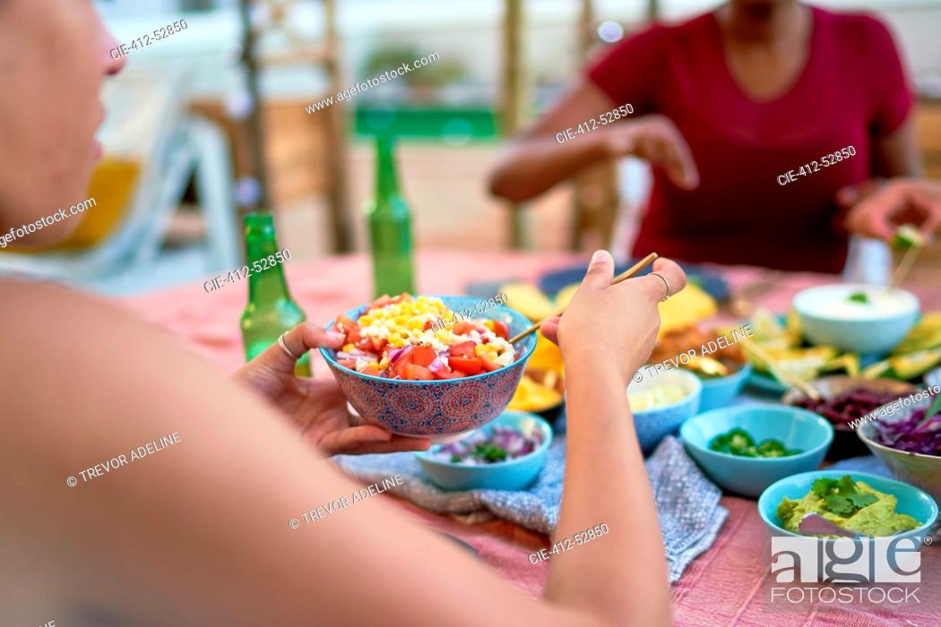 Photo de stock: Young woman eating lunch at patio table.