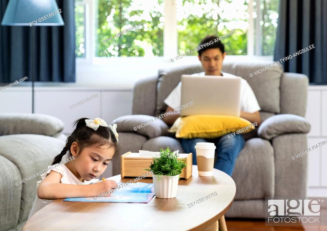 Stock Photo: Asian girl drawing in living room with his father working from home with laptop notebook in background while city lockdown from coronavirus covid-19 pandemic.