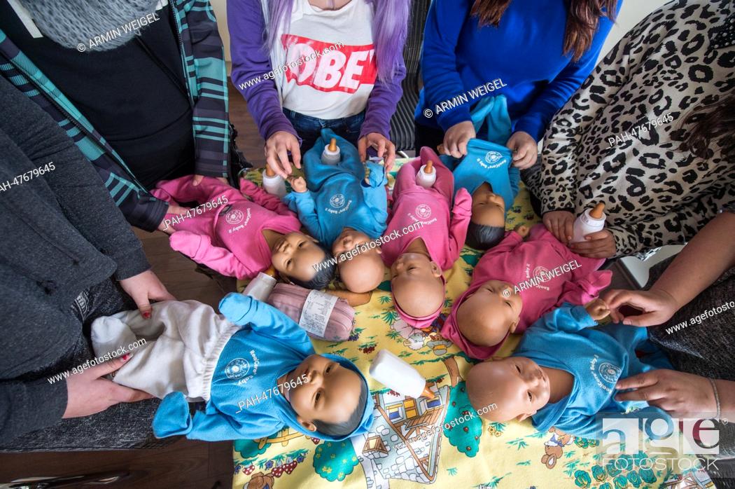 Stock Photo: Teenage girls look after lifelike baby dolls during an internship for parents to prevent young people to get children in Amberg, Germany, 31 March 2014.