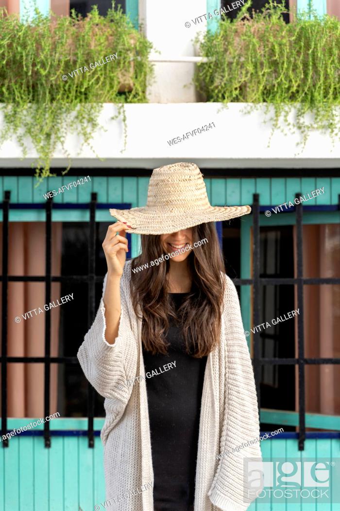 Stock Photo: Young woman wearing sun hat, hand on hat.