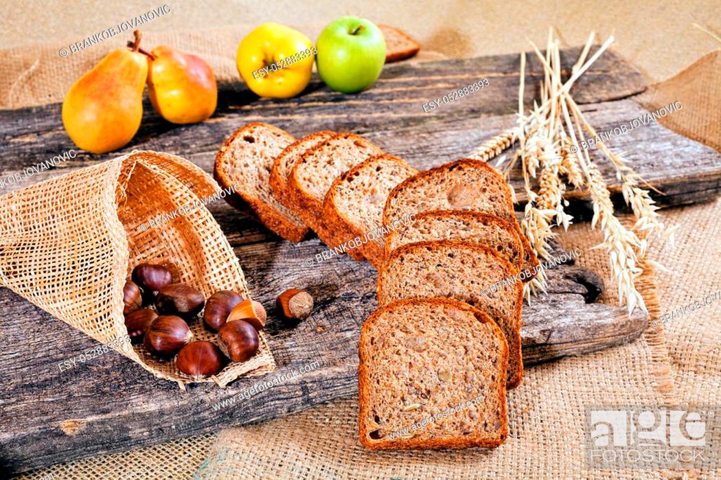 Stock Photo: arranged of bread with seeds, fruits and chestnuts on the wooden board, note shallow depth of field.