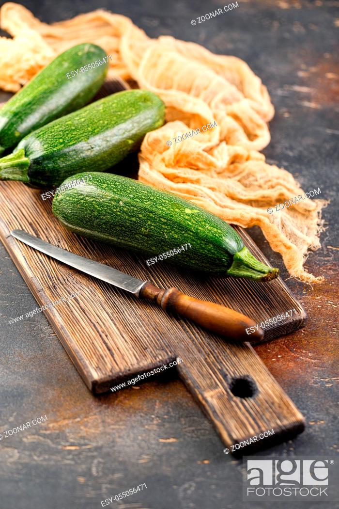 Stock Photo: Three fresh zucchini squash on a wooden cutting board.