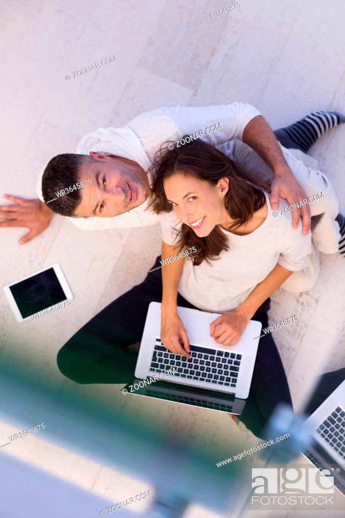 Stock Photo: top view of a young couple relaxing at home with tablet and laptop computers reading on the floor.