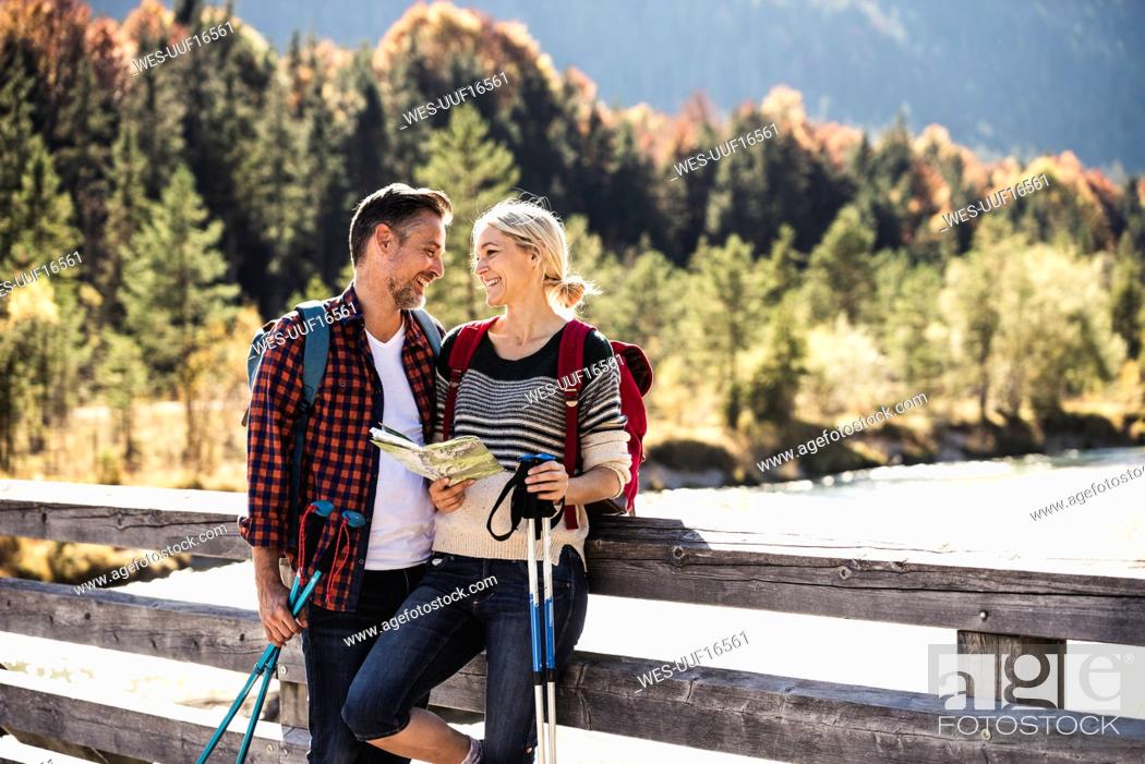 Stock Photo: Austria, Alps, happy couple on a hiking trip with map on a bridge.