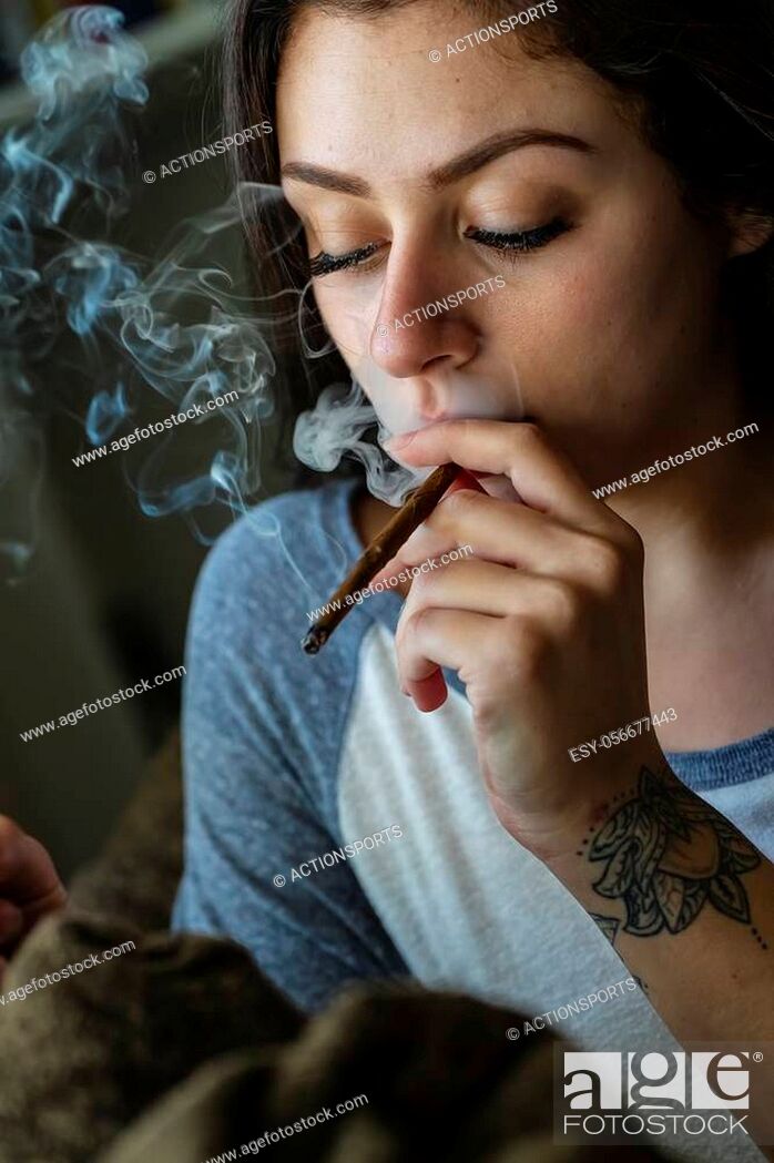 Stock Photo: A beautiful brunette model smokes marijuana in the privacy of her own home.
