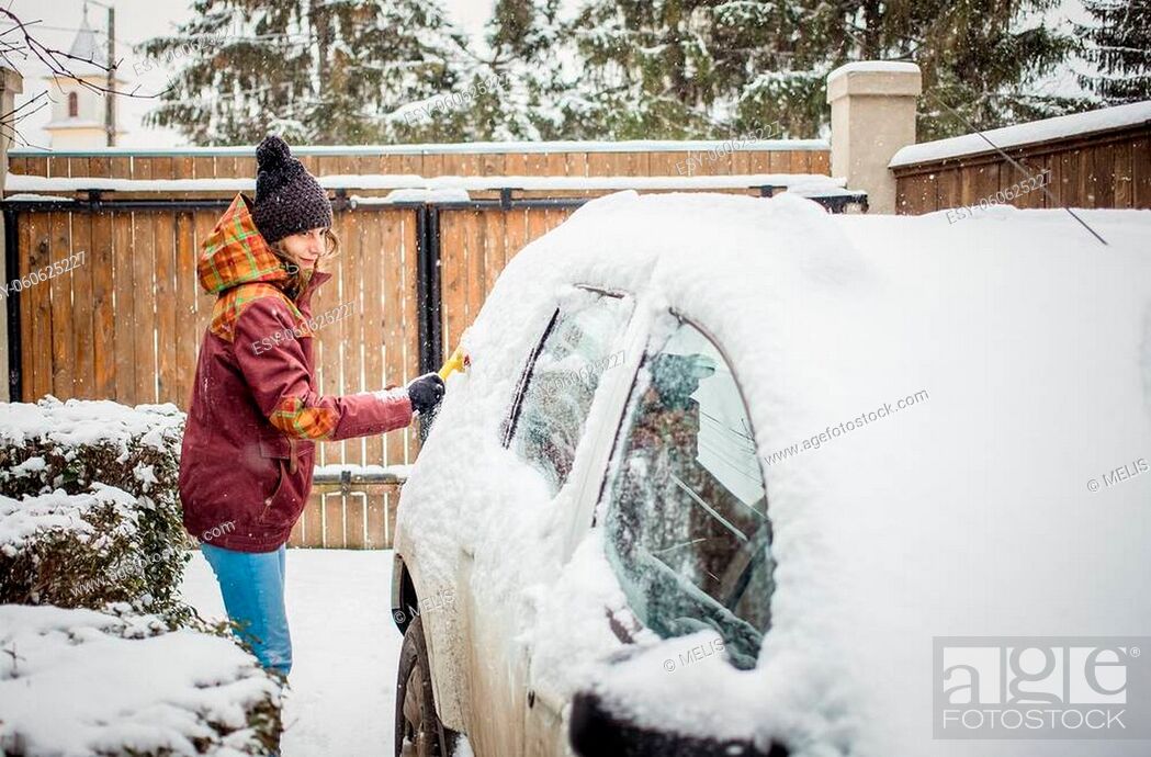 Stock Photo: woman cleaning snow from car after blizzard.