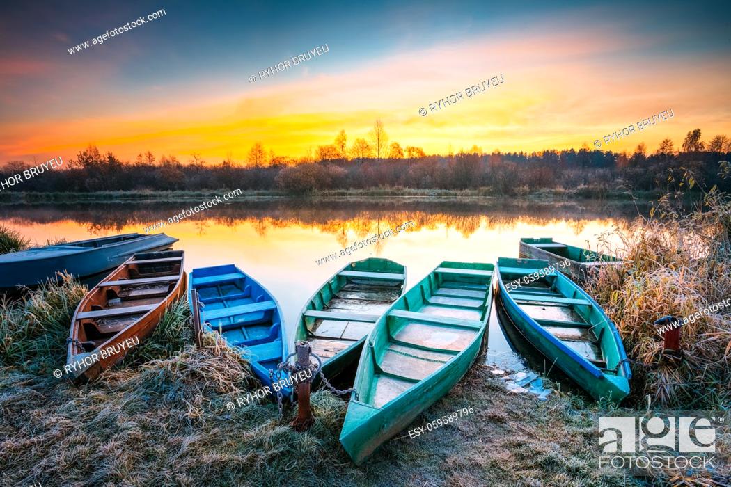 Stock Photo: Lake, River and rowing fishing boat at beautiful sunrise in autumn morning. Old wooden boats and frosted grass.