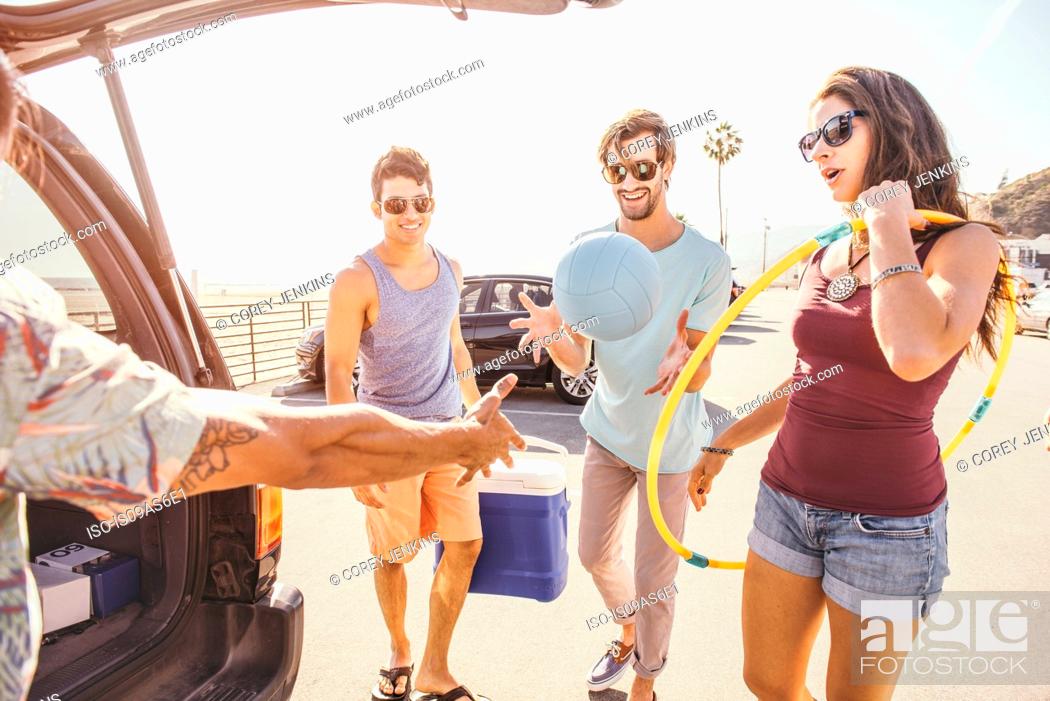 Stock Photo: Group of friends standing by car, holding picnic and play items.