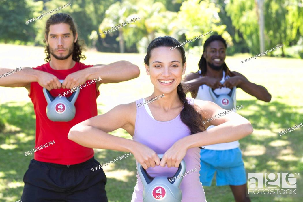 Stock Photo: Fitness group working out in park with kettle bells.