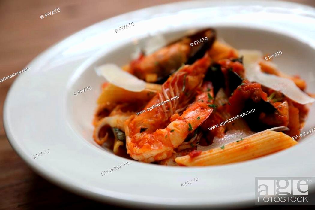 Stock Photo: Penne pasta tomato sauce arabiata with seafood on wood background vintage style.