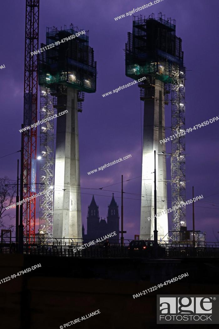 Stock Photo: 22 December 2021, Saxony-Anhalt, Magdeburg: View of the construction site with the two pylons at dusk. The new construction of the Strombrücke was started in.