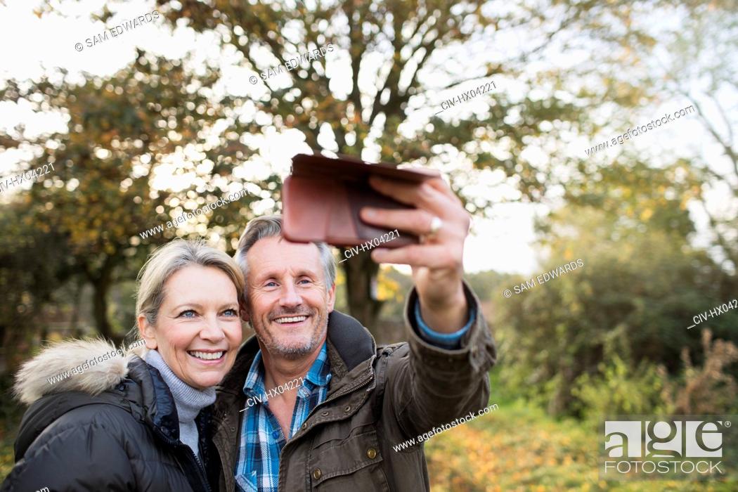 Stock Photo: Happy mature couple taking selfie with camera phone in autumn woods.