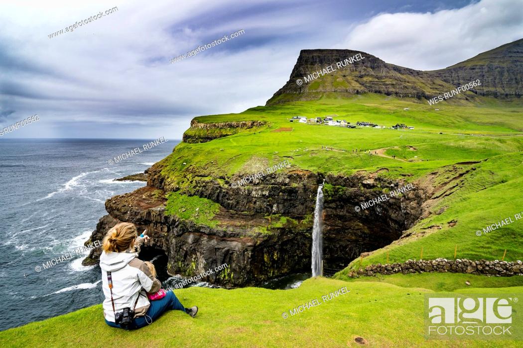 Stock Photo: Denmark, Faroe islands, Vagar, Woman and her daughter looking at the Gasadalur waterfall.