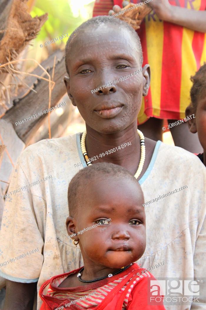 Stock Photo: Internally displaced Nyakume Wuor Gai stands together with her youngest daughter in front of a shed on an island near Nyal at the federal state Unity, Uganda.