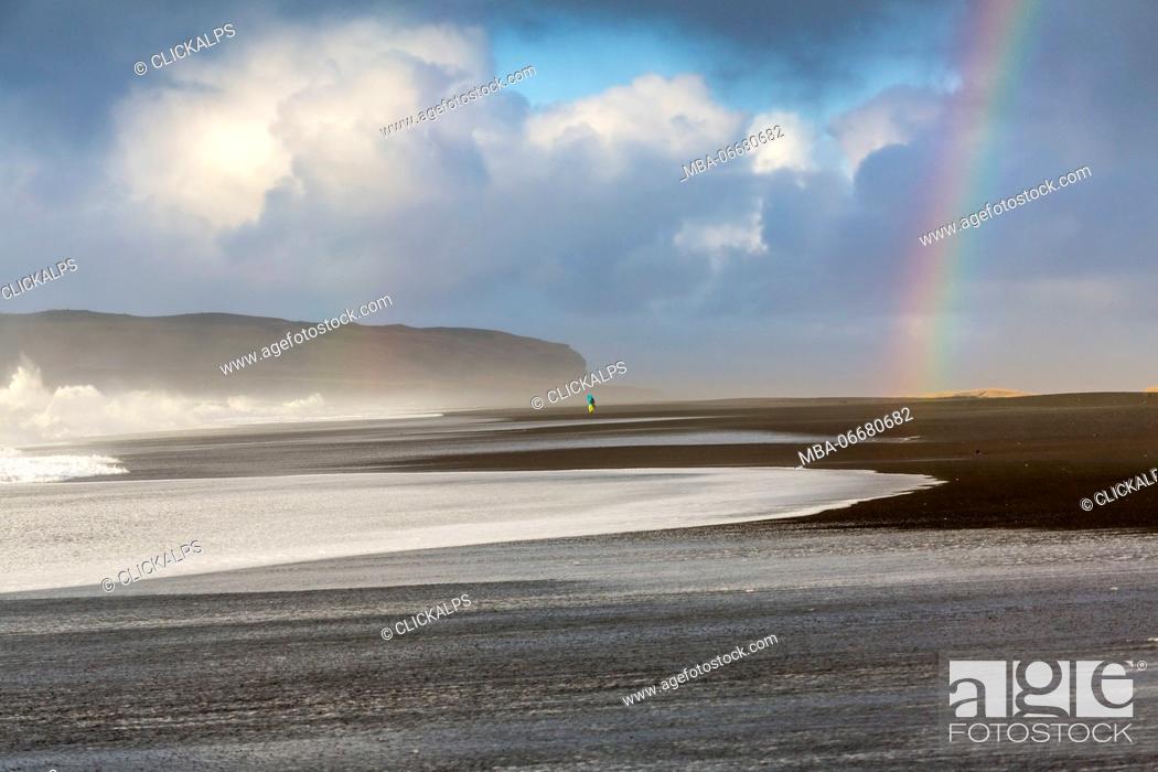 Stock Photo: A man is walking towards the rainbow on the beach of Reynisfjara, Vik, Sudurland, Iceland, Europe.