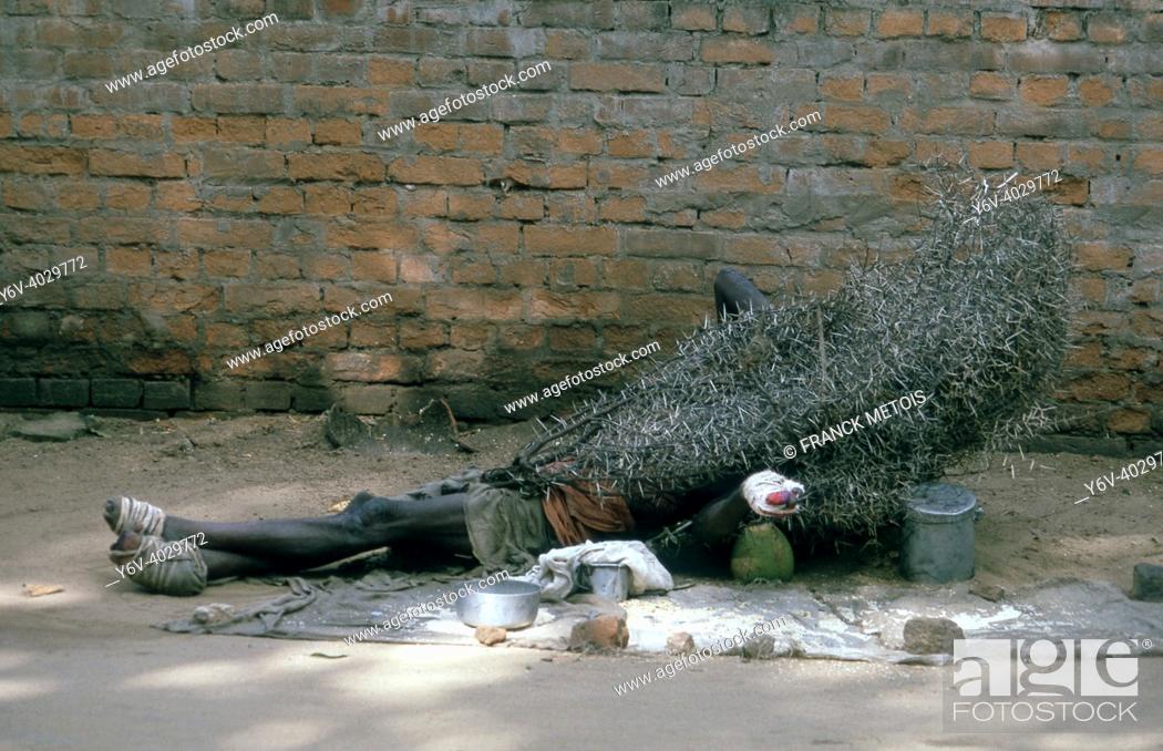 Stock Photo: A leper is begging on the street while lying on the ground under a thorny bush ( Odisha, India).