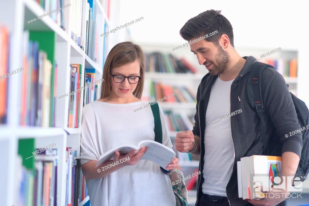 Stock Photo: happy students couple in school library have discussion about book.