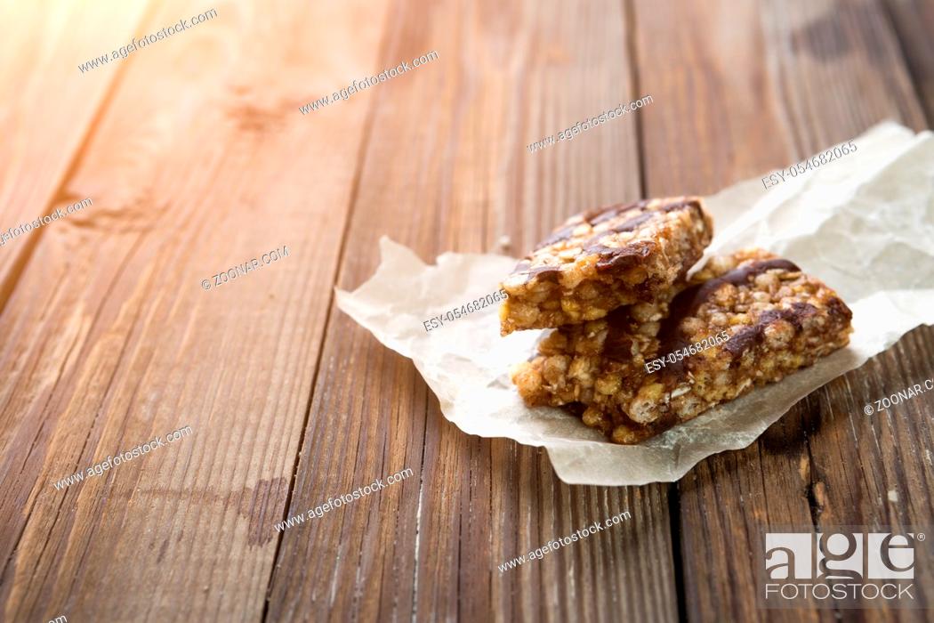 Stock Photo: Granola with chocolate on paper on wooden table.