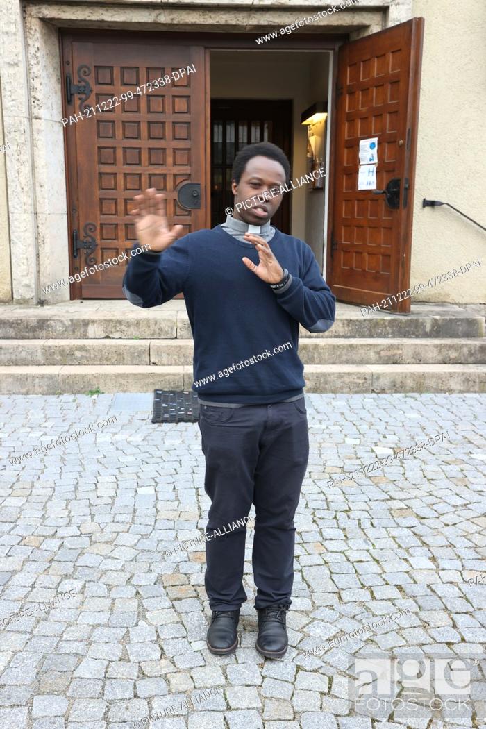 Stock Photo: PRODUCTION - 19 December 2021, Thuringia, Weimar: Jean-Francois Uwimana, a priest from Rwanda, raps the Gospel in front of St. Boniface Church.