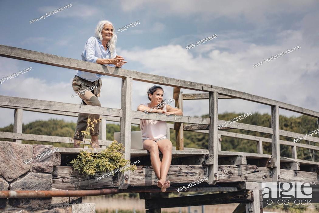 Stock Photo: Mother and daughter looking at view from a bridge.