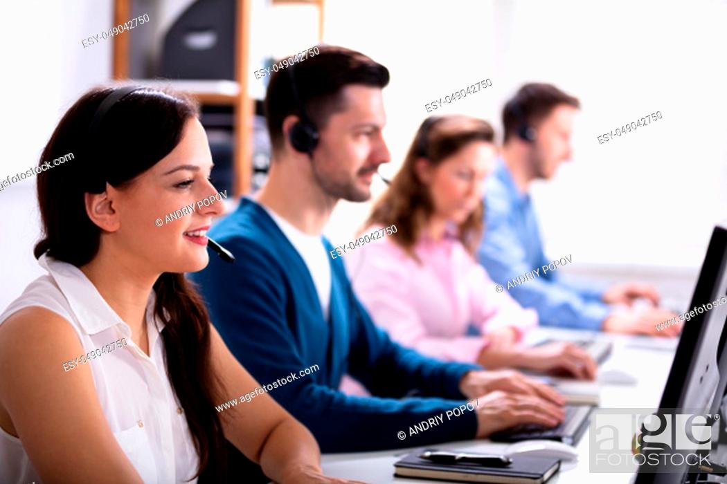 Stock Photo: Happy Young Customer Service Executives Using Earphones Working In Call Center.