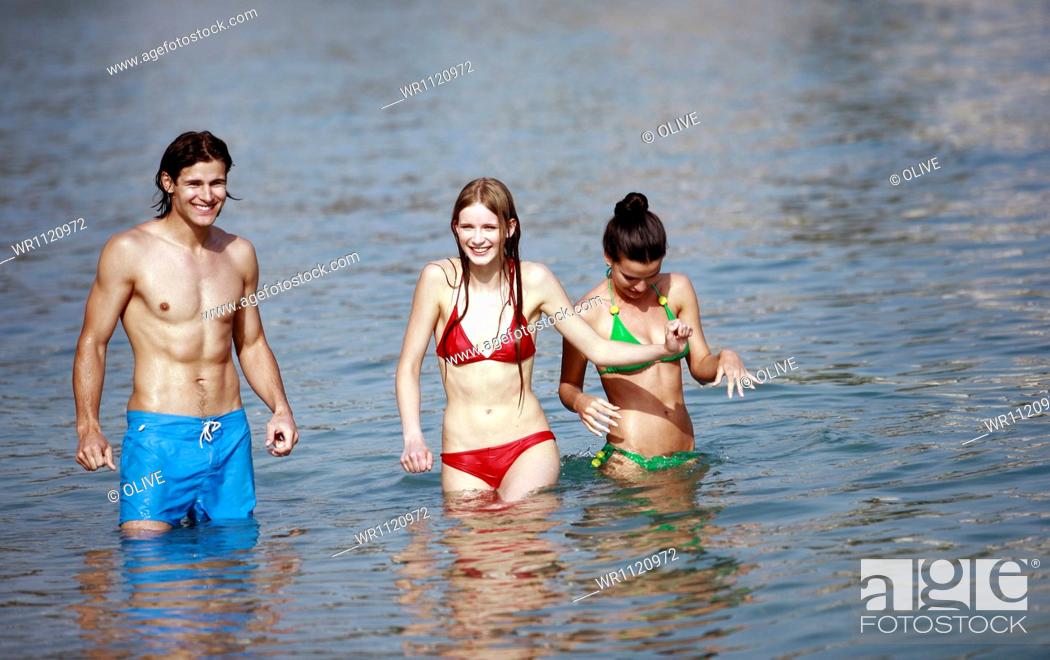 Stock Photo: Young Adult, Looking At Camera, Dark Hair, Brown Hair, Full Length, Color Image, Man, One, Outdoors, Sea, Summer, Adult, Beach, Caucasian Appearance, Leisure, Woman, Bathing, Suit, Happy, Smile, Swimsuit, Bikini, Horizontal, Relaxation, Sand, Fun, View, Swimming, Friendship, Group