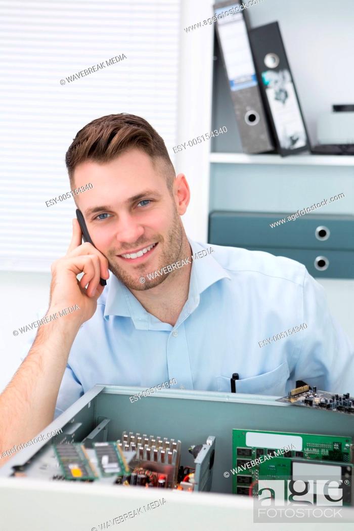Stock Photo: Portrait of smiling computer engineer on call in front of open cpu.