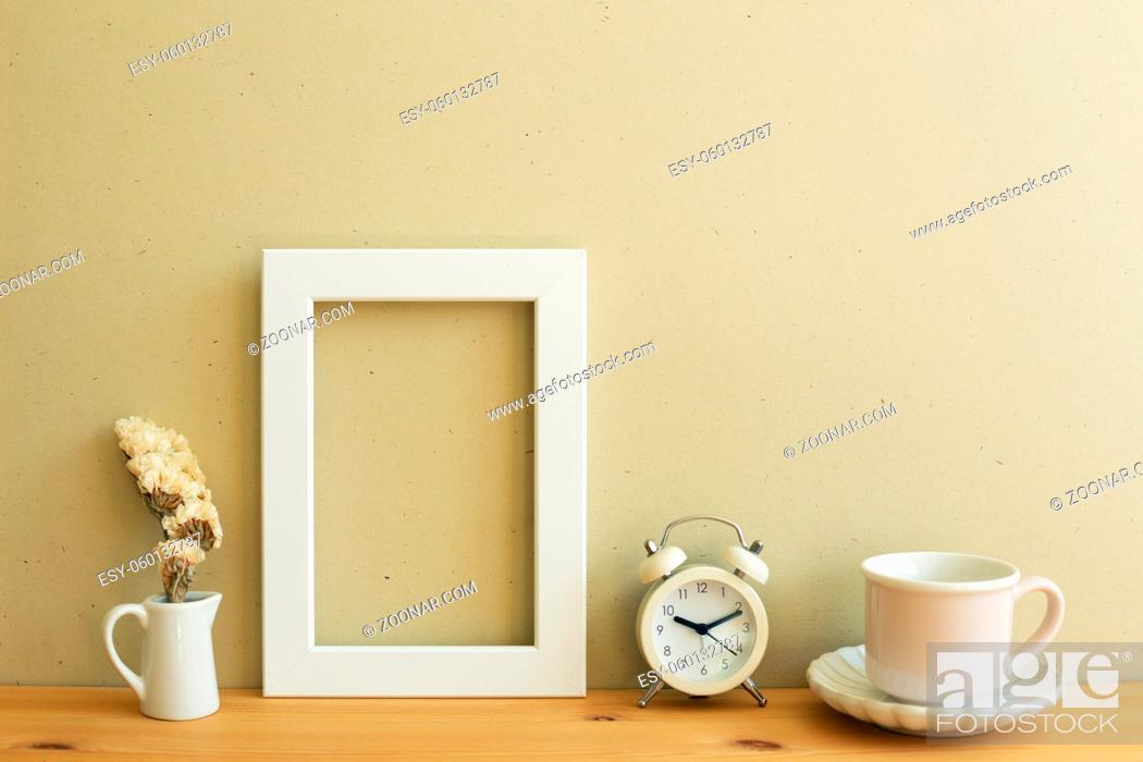 Stock Photo: White photo frame, dry flower, clock, coffee cup on wooden table. beige wall background. home interior.