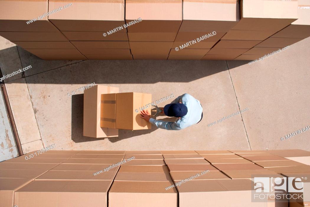 Stock Photo: Worker standing with boxes and hand truck.