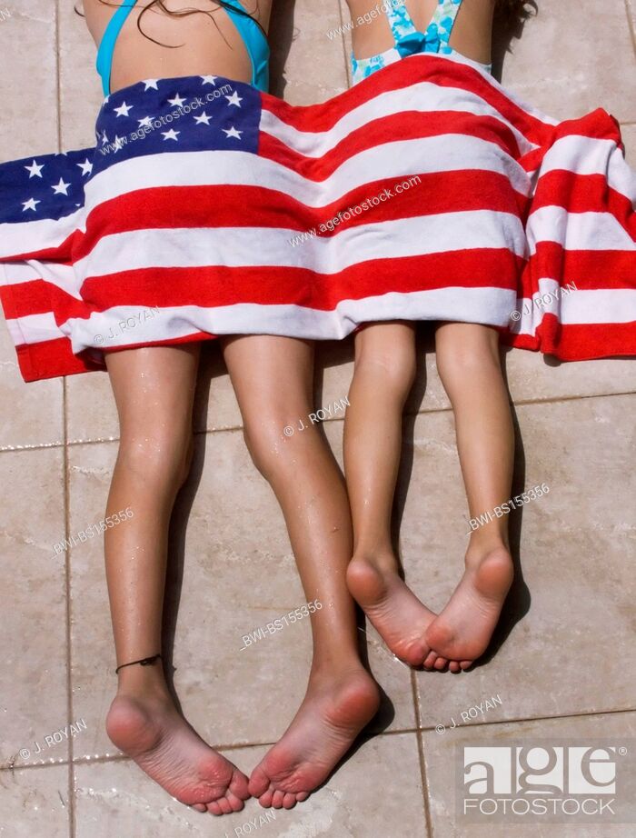 Stock Photo: two girls lying in the sun with an american flag towel covering them, USA.