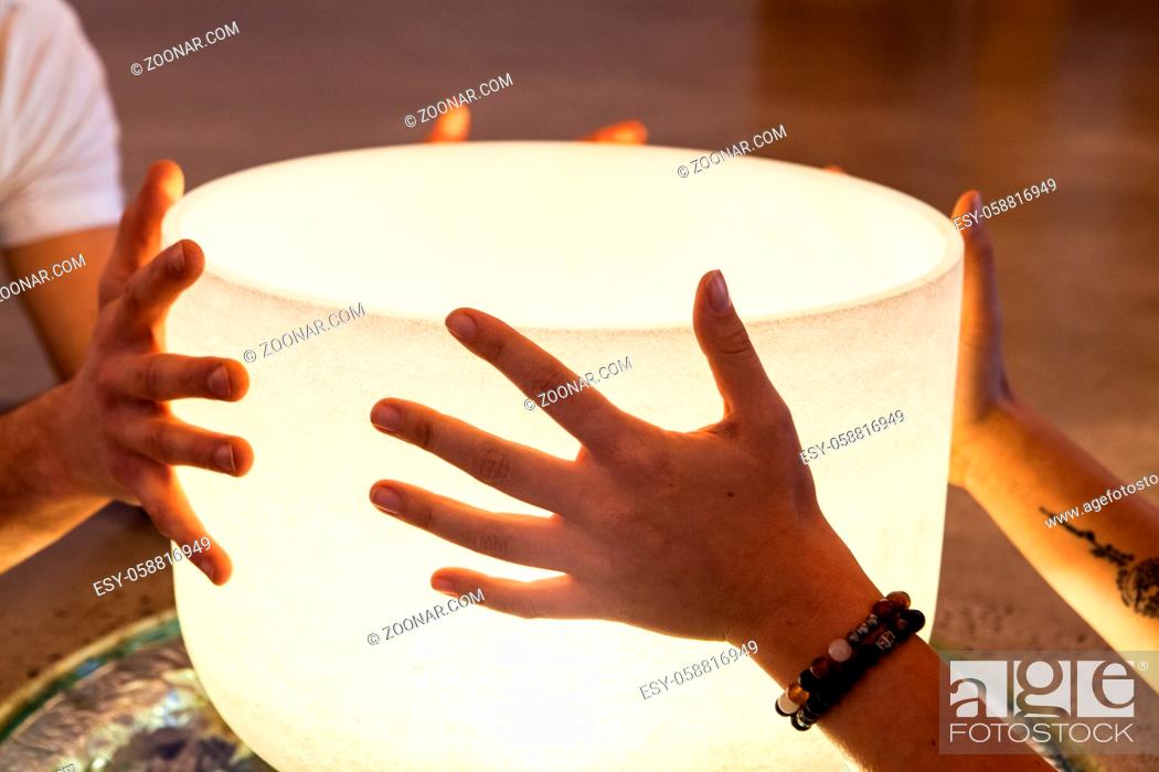 Stock Photo: Two young hands holding each a side of a crystal ball. The girls wears bracelets. Closeup shot.