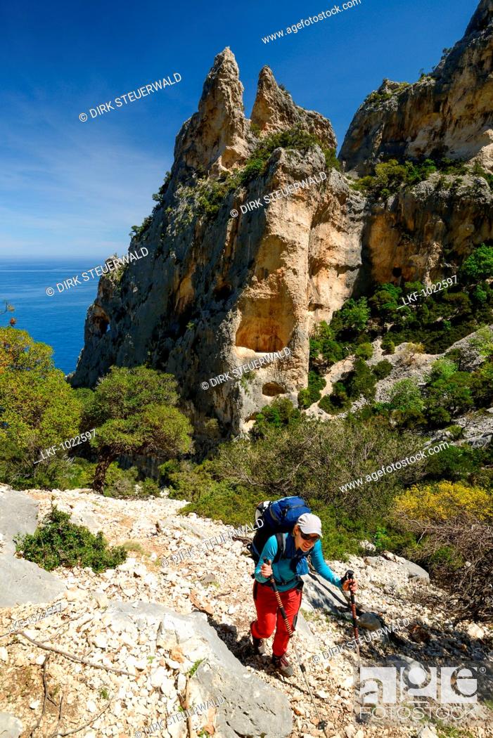 Stock Photo: A young woman with trekking gear hiking along the mountainous coast above the sea, Golfo di Orosei, Selvaggio Blu, Sardinia, Italy, Europe.