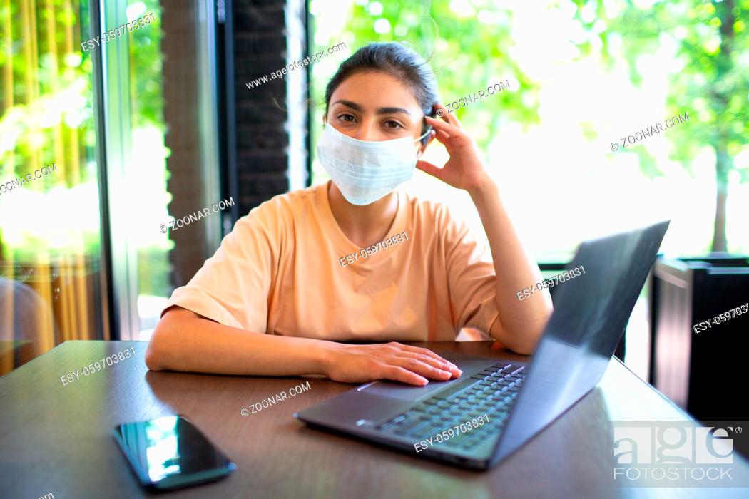 Stock Photo: Indian business coaching woman working on her laptop outdoor with mobile phone and face mask.