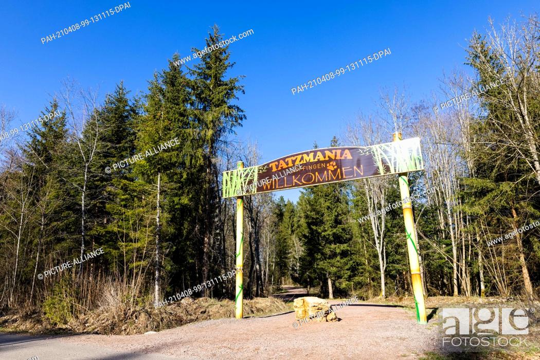 Stock Photo: 08 April 2021, Baden-Wuerttemberg, Löffingen: A sign reading ""Tatzmania - Löffingen - Welcome"" hangs over a path leading to the entrance of the zoo.