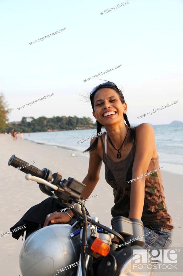 Stock Photo: Cambodschanische young woman with a motorcycle on the beach in Sihanoukville.