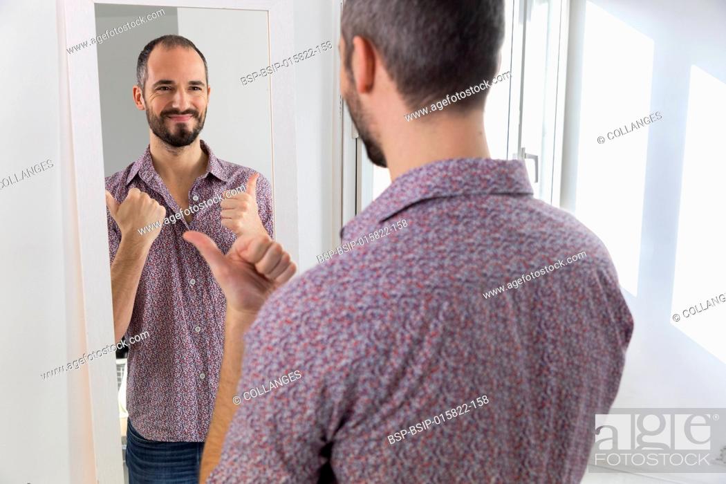 Stock Photo: A man looking in a mirror to give him self-confidence.