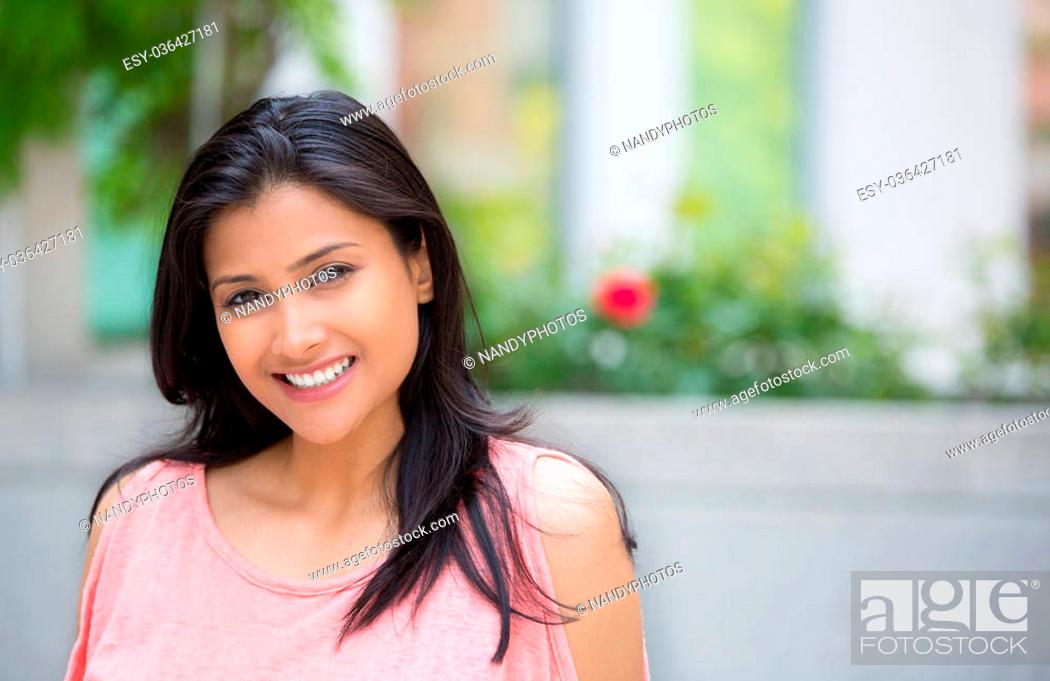 Stock Photo: Closeup portrait of confident smiling happy pretty young woman in pink dress, isolated background of blurred trees, flowers.
