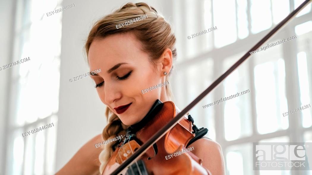 Stock Photo: Young Attractive Woman In A Beautiful Dress Is Playing The Violin. The Violinist Is Full Of Inspiration And Excitement.
